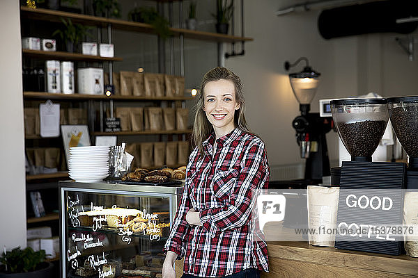 Porträt einer lächelnden Frau an der Theke eines Cafés