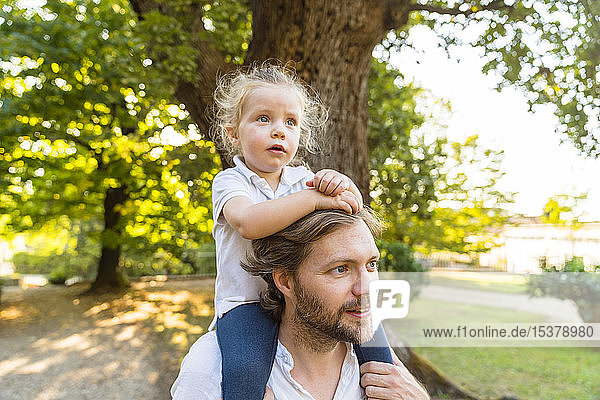 Father carrying little daughter on his shoulders