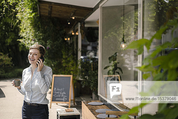 Glückliche Geschäftsfrau benutzt Handy in einem Cafe
