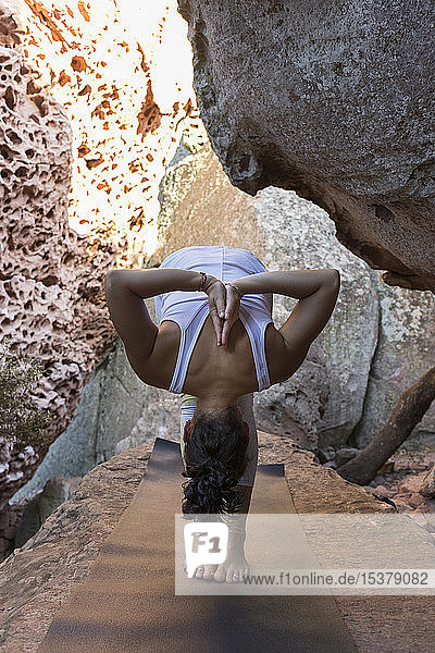 Junge Asiatin praktiziert Yoga auf einem Felsen