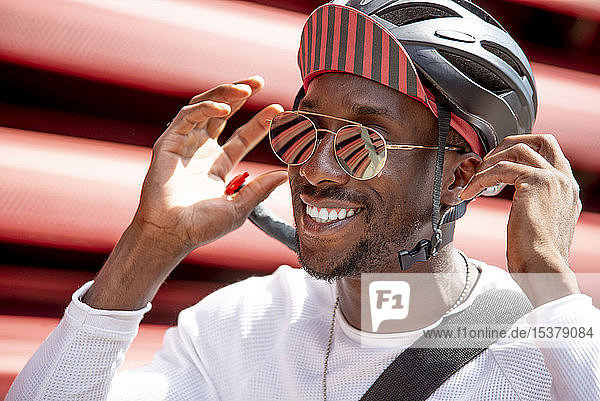 Lächelnder junger Mann setzt seinen Fahrradhelm auf