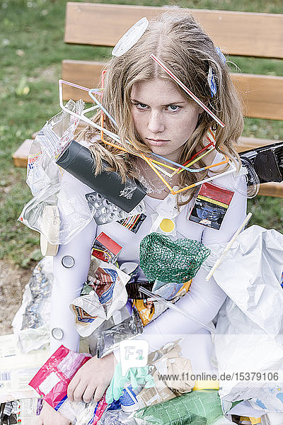 Teenager wearing white dress with plastic waste  next to a