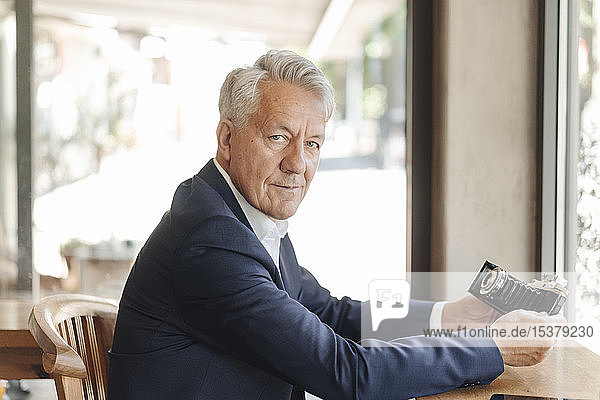 Porträt eines hochrangigen Geschäftsmannes mit altmodischer Kamera in einem Cafe