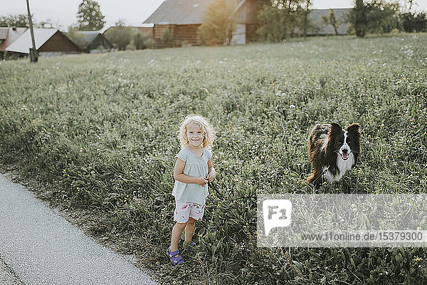 Mädchen geht mit Hund auf dem Land spazieren