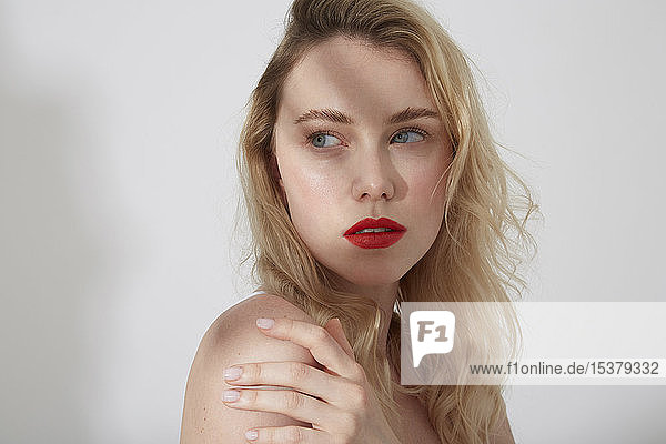 Bildnis einer jungen blonden Frau mit roten Lippen und Schatten im Gesicht