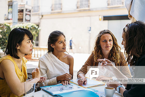 Weibliche multikulturelle Studentinnen treffen sich in einem Café und organisieren ihren Stundenplan