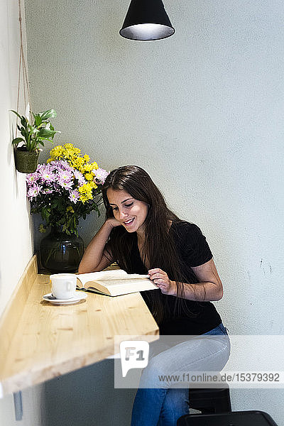 Young woman reading a book in a cafe