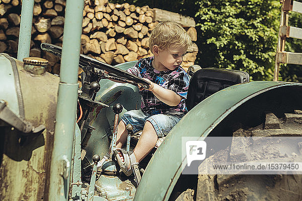 Kleiner Junge  der vorgibt  einen Traktor zu fahren