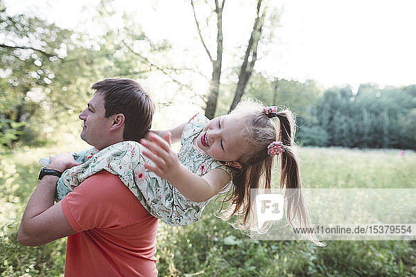 Father carrying playful daughter on his shoulders