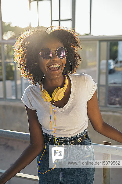 Portrait of laughing young woman with sunglasses and headphones