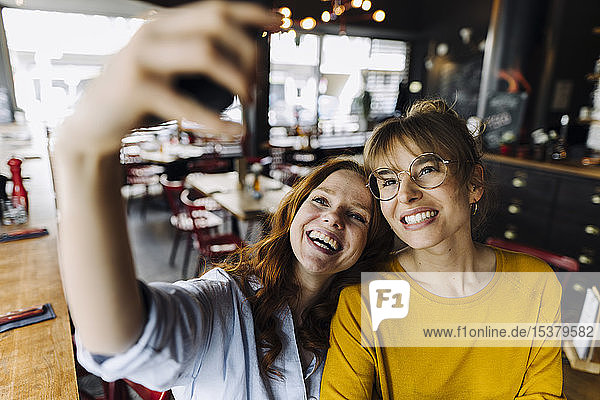 Zwei glückliche Freundinnen beim Selfie in einem Restaurant