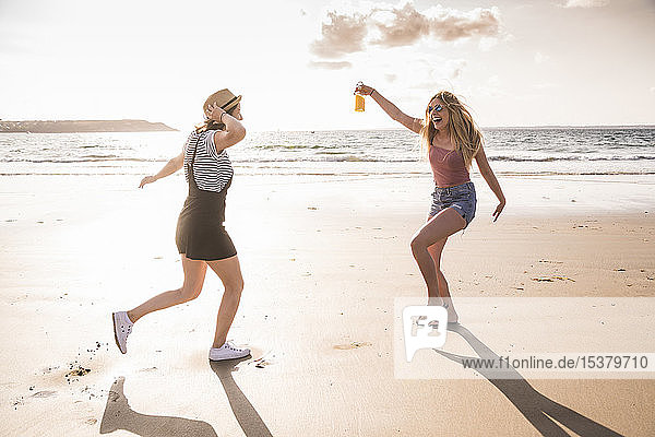 Two girlfriends having fun  running and jumping on the beach