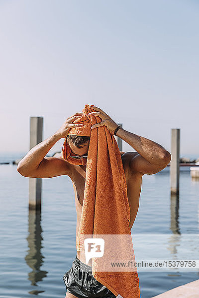 Junge mna trocknet sein Haar mit einem Handtuch am Meer