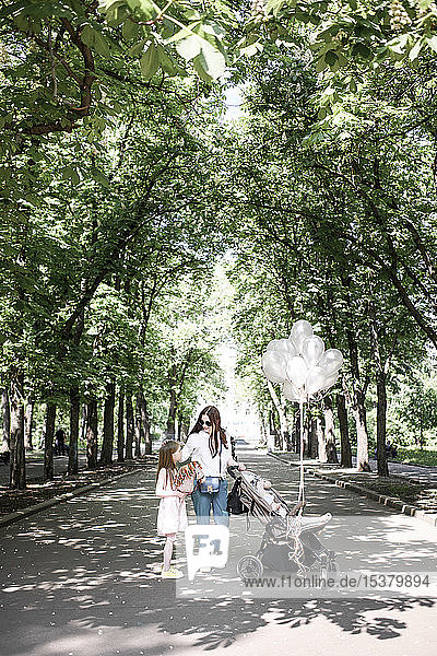 Mutter mit ihren zwei Kindern und Luftballons im Park