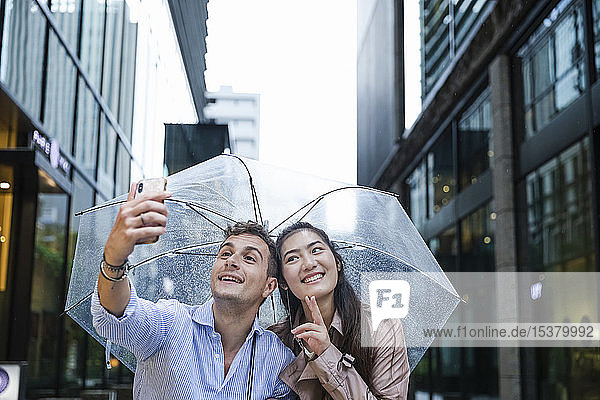 Glückliches Paar mit Regenschirm beim Selfie in Ginza  Tokio  Japan