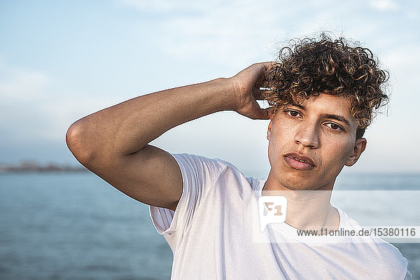 Portrait of young man with curly hair by the sea