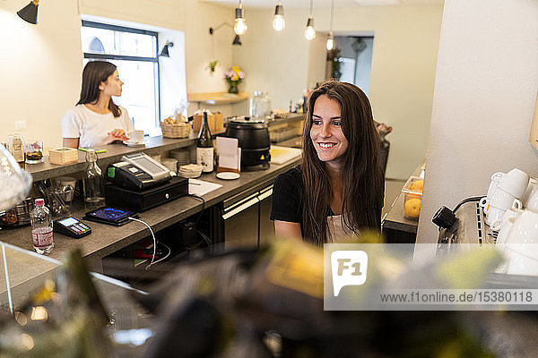 Lächelnde junge Frau hinter der Theke eines Cafés