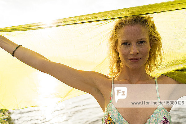 Porträt einer jungen Frau  die ein Tuch an einem See hält