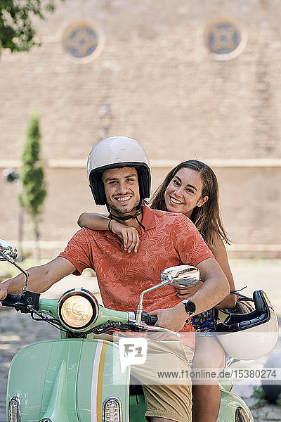 Porträt eines lächelnden jungen Paares auf einem Oldtimer-Motorroller