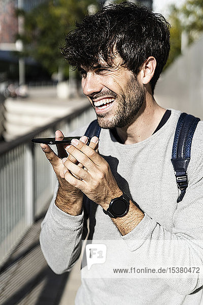 Happy man using smartphone in the city