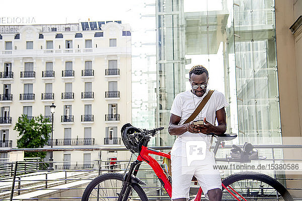 Junger Mann an seinem Fahrrad mit seinem Smartphone