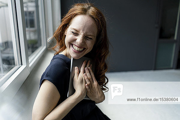 Porträt einer lachenden rothaarigen Geschäftsfrau mit digitalem Tablet in einem Loft