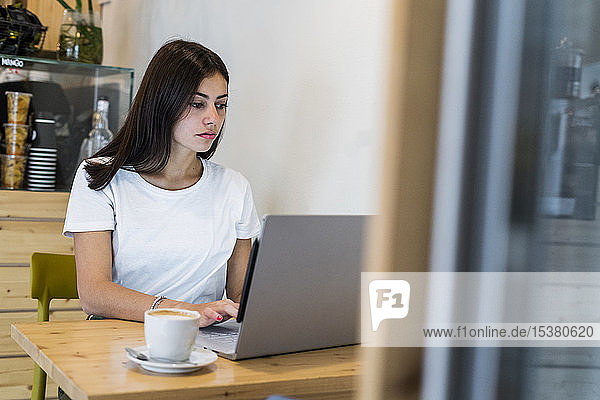Young woman using laptop in a cafe