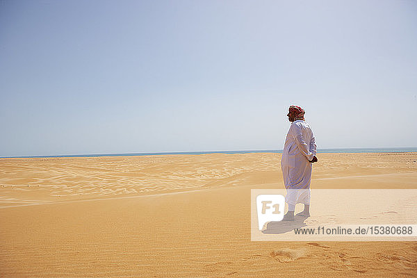 Beduine in Nationaltracht in der Wüste stehend  Rückansicht  Wahiba Sands  Oman