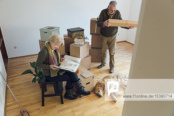 Älteres Ehepaar mit Hund  umgeben von Pappkartons in einem leeren Raum