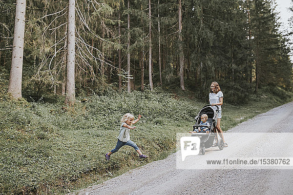Mutter mit Tochter und Baby im Kinderwagen im Wald