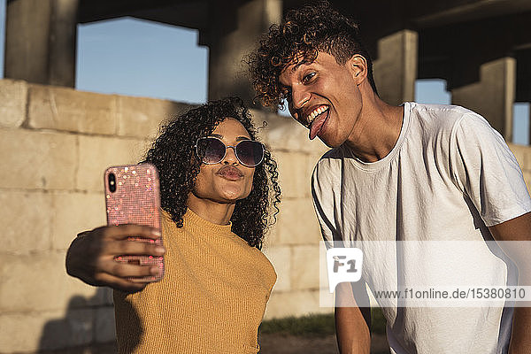 Junges Paar  das sich mit einem Smartphone selbstständig macht und vor der Wand sitzt