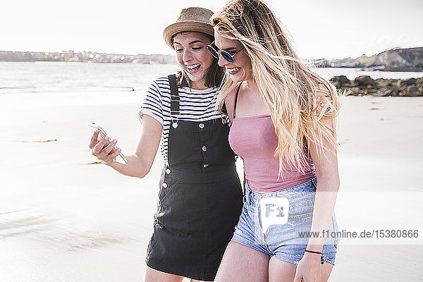 Zwei Freundinnen amüsieren sich  gehen auf dem Smartphone