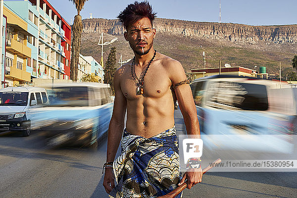Tribal man with his traditional arch and arrows in the middle of the city with cars passing by  Lubango  Angola