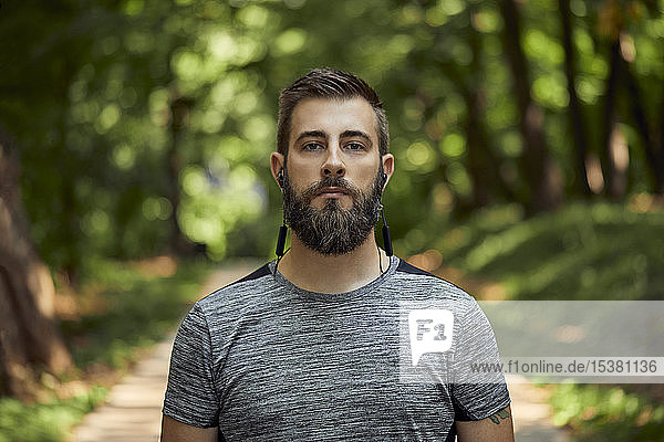 Portrait of sporty man with earphones in forest