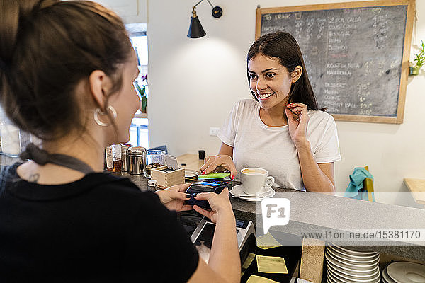 Customer paying cashless with smartphone in a cafe