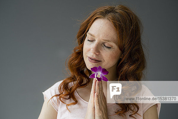 Bildnis einer rothaarigen Frau mit lila Orchideenblüte