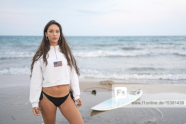 Porträt einer jungen Frau mit Surfbrett am Strand
