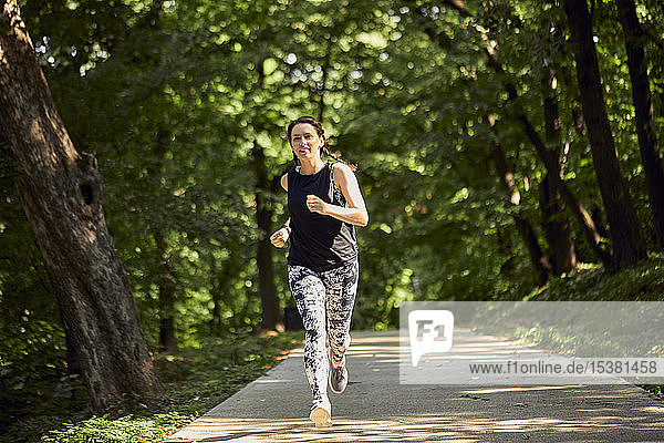 Sportliche junge Frau rennt auf Waldweg