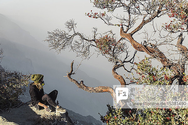 Frau mit Atemschutzmaske sitzt am Vulkan Ijen  Java  Indonesien