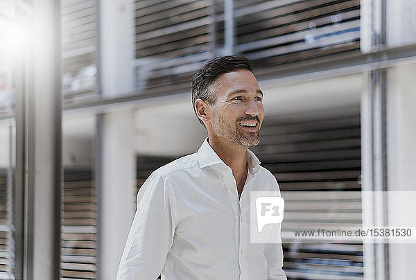 Lächelnder Geschäftsmann auf einem Parkplatz mit weißem Hemd