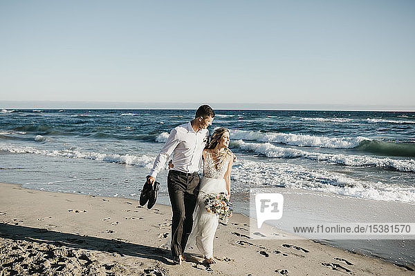 Braut und Bräutigam beim Spaziergang am Strand