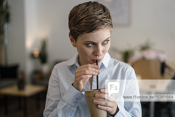 Geschäftsfrau in einem Café  die aus einem Becher trinkt