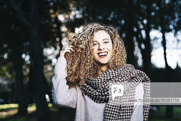 Porträt einer lachenden jungen Frau mit Ringellöckchen in einem Park
