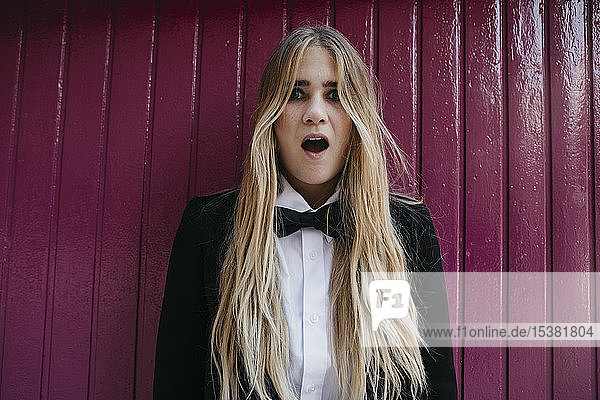 Porträt einer überraschten jungen Frau mit schwarzer Krawatte und Blazer