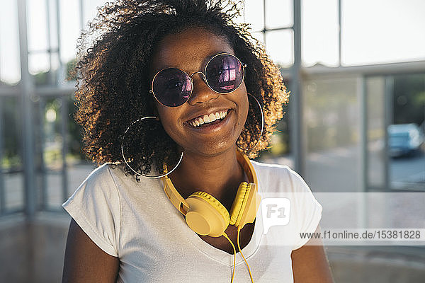Porträt einer glücklichen jungen Frau mit Kopfhörer und Sonnenbrille