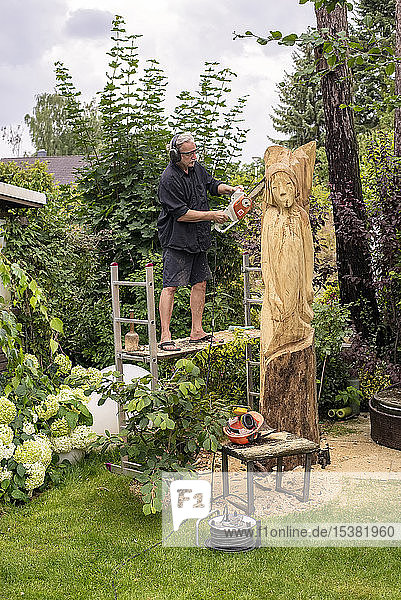 Holzschnitzerin schnitzt Skulptur  Engel  mit Kettensäge