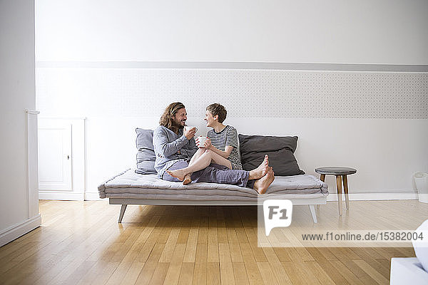 Happy young couple in pyjamas on bed couch at home