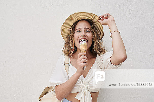 Porträt einer glücklichen jungen Frau mit Hut beim Eisessen