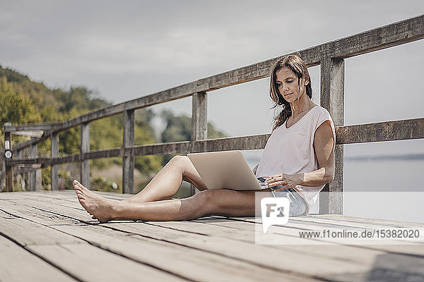 Woman sitting on wood bridge  using laptop