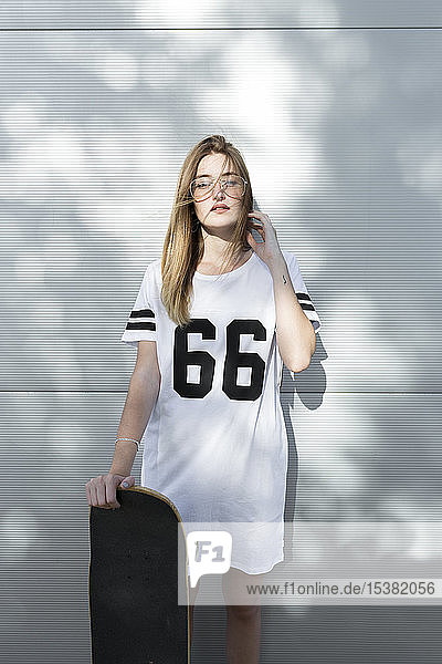Junge Frau trägt T-Shirt mit der Nummer 66  hält Skateboard